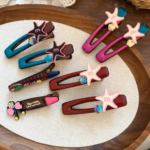 Detailed macro view of star-shaped acetate hair clips with flower accents on a wood tray