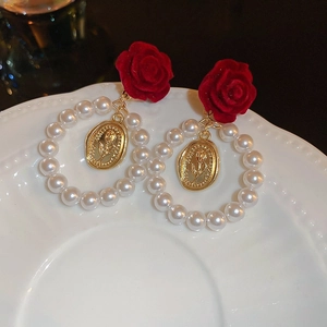 Detail of velvet red rose earrings with pearl hoop and gold embossed floral pendant