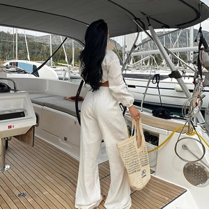 Vue arrière du mannequin sur un yacht portant un ensemble plissé blanc deux pièces
