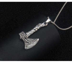 Close-up of vintage silver viking axe pendant with embossed runes and metal chain