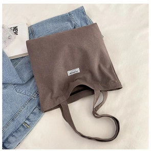 Detailed view of brown canvas tote bag featuring Fashion label on beige fabric