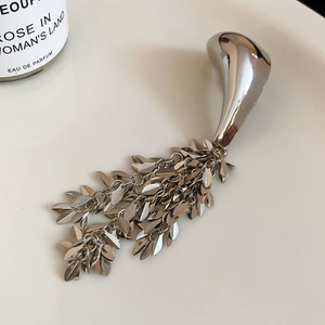 Detail of silver waterdrop earring featuring tiered leaf tassels with a metallic finish