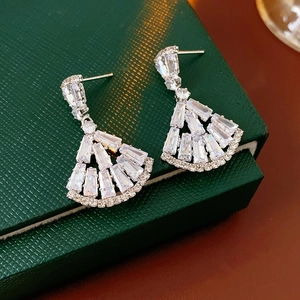Macro shot of silver fan-shaped earrings with white zircon on green jewelry box