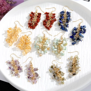 Macro detail of natural stone tassel earrings with golden hooks on white ceramic tray