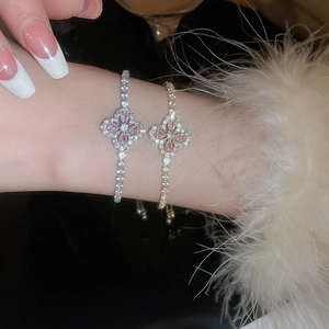 Détail de bracelets élégants en or et argent avec pendentifs fleurs en zircon rose au poignet