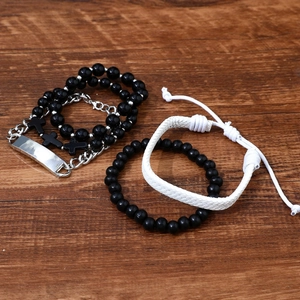 Three-piece men's beaded bracelet set with cross charms on a dark wood background