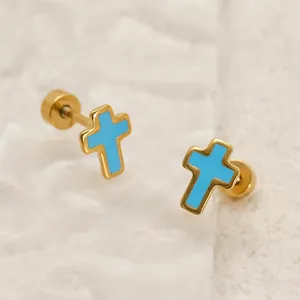 Fashionable gold cross stud earrings with blue enamel finish on white textured surface