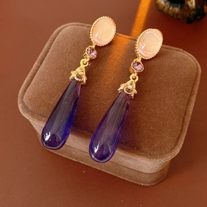 Détail de boucles d'oreilles vintage avec résine violette et métal doré finement ciselé