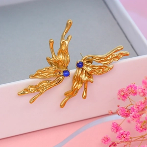 Detailed macro view of gold butterfly wings earrings featuring round blue cat eye stone