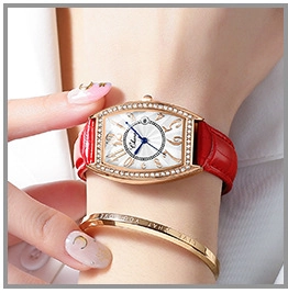 Close-up of women's gold tonneau watch with red leather strap and sparkling crystal bezel
