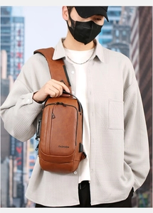 Detail of vintage brown chest bag showing built-in USB charging port and zipper design