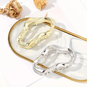 Detail shot of wavy gold and silver metal hair claws on a marble tray for hair styling