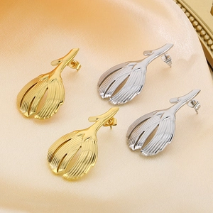 Macro view of gold and silver leaf earrings with textured metal stripes on silk background