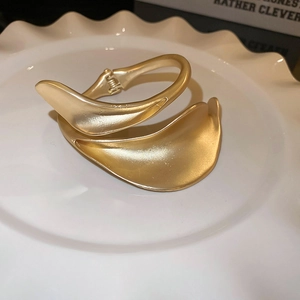 Macro detail of golden matte brushed wide bangle on a white ceramic textured tray