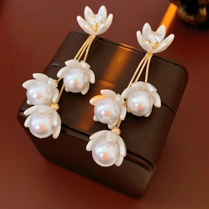 Close-up of elegant flower stud earrings with gold tassels and pearl pendants