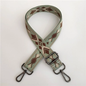 Detail of adjustable green jacquard woven strap with geometric patterns and metal hooks