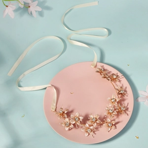 Bohemian gold flower bridal headband with rhinestones and white ribbons on light blue background