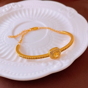 Gros plan d'un bracelet doré avec pierre jaune sur une assiette en céramique blanche