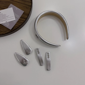 Flat lay of silver Y2K PU leather headband and star hair clips set on white desk