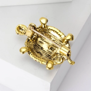 Back view of gold turtle brooch showing secure safety pin clasp and textured metal finish