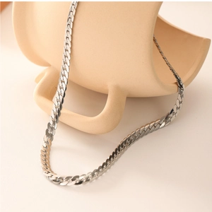 Detailed view of silver stainless steel flat snake chain on a ceramic plate