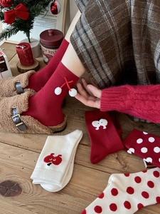 Detail of red and cream knitted Christmas socks with cute bow and 3D pom-pom accents