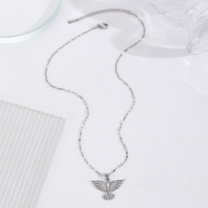 Close-up of silver eagle pendant with white rhinestones on a delicate chain necklace