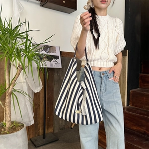 Détail du sac cabas en toile à rayures bleues et blanches avec bordure en dentelle fine