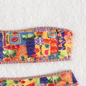 Detailaufnahme des lebendigen Bikini-Stoffs mit tropischem Fruchtprint auf weichem Grund