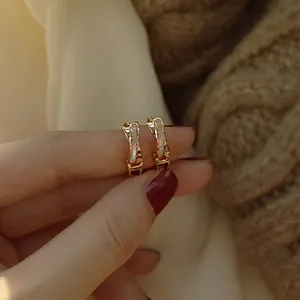 Detail of a vintage golden round earring with white inlay held in hand