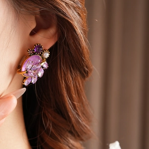 Close-up detail of vintage gold earrings with purple zircon and pearl floral design