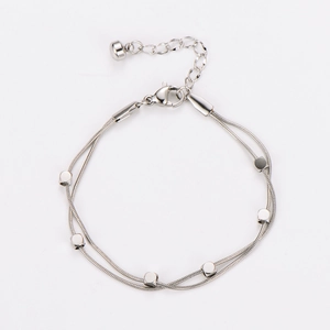 Detail of silver double-layered snake chain bracelet with square metal charms