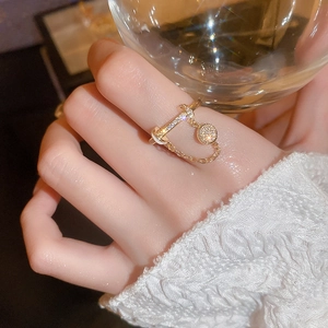 Nahaufnahme des goldene Quastenring mit Zirkonia-Anhänger und Kette am Zeigefinger