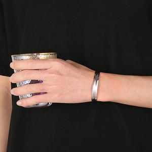 Dettaglio del bracciale a fascia in argento a forma di C con texture sfaccettata