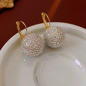Detail of gold ball hoop earrings with colorful pavé rhinestones in a white ceramic dish