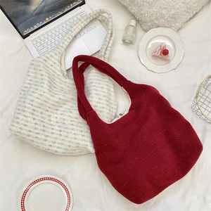 Detail view of large plush tote bags in dark red wool and striped tweed on white bedding