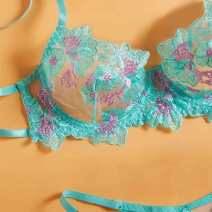 Teal lace bra set with purple floral embroidery and sheer mesh on orange background