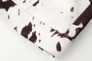 Macro detail of cow print cropped jacket showing velvet texture and double stitching