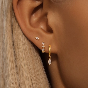 Close-up of three gold 925 silver star and marquise stud earrings on a model's ear