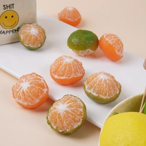 Realistic peeled orange and green tangerine models displayed on white podium