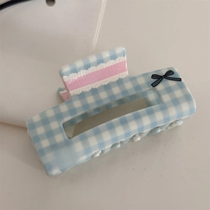Detail of blue gingham hair claw clip with pink lace stripes and black bow accents
