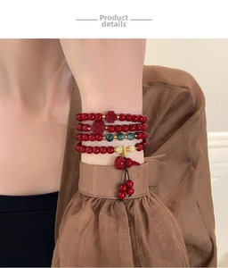 Detail of multi-layer red beaded bracelet featuring Fu pendant and gourd charms