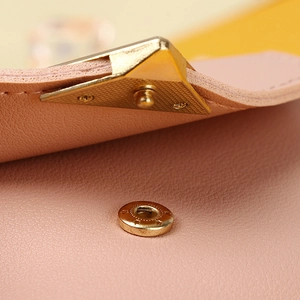 Close-up of pink leather wallet featuring golden magnetic snap and litchi texture