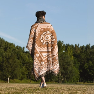 Detail of bohemian woven camping blanket with geometric patterns and fringe outdoors