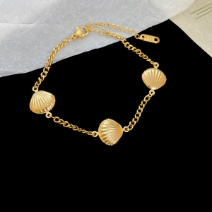 Macro detail of gold stainless steel bracelet with shell charms and K18 hallmark
