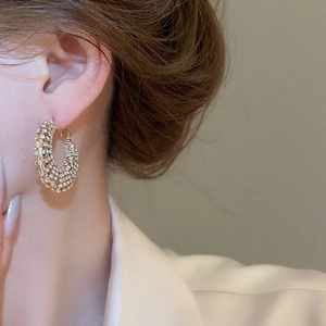 Close-up of elegant gold C-shaped hoop earrings with shimmering pave crystals on a model