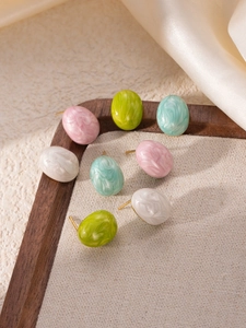 Close-up of marble textured oval stud earrings in pastel colors on wood tray