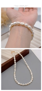 Detailed view of warm white baroque pearl necklace with a gold lobster clasp on hand