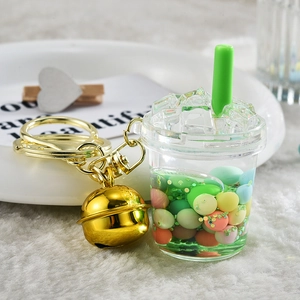 Detail of creative milk tea cup keychain with green liquid and golden bell accessories