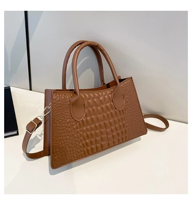 Detailed macro view of the glossy faux crocodile texture on this caramel handbag